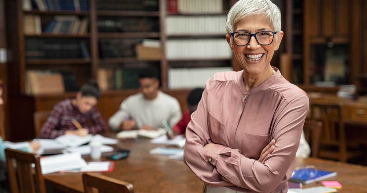 avaliação dos docentes da IES - Professor universitário sorridente na biblioteca